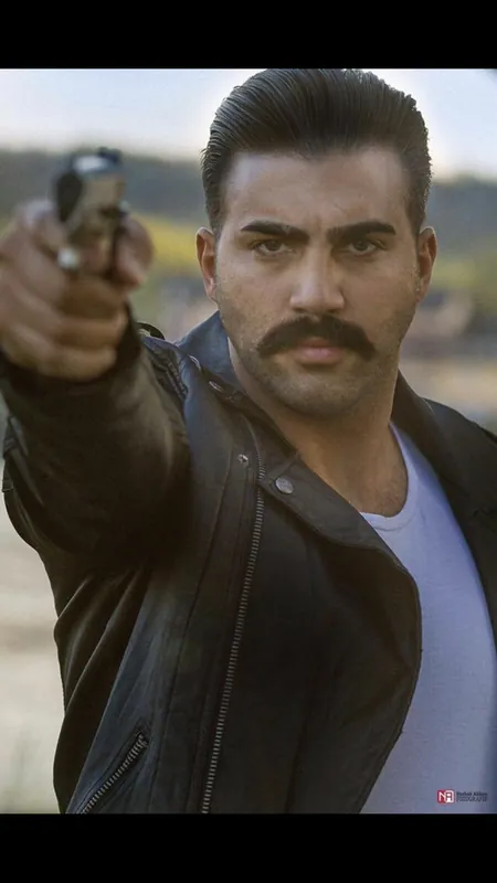 Ömer Kaya in Lederjacke zielt bei einem Schauspiel-Shooting mit einer Pistole