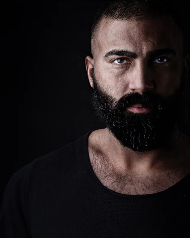 Dunkles Studioporträt von Ömer Kaya mit schwarzem Vollbart