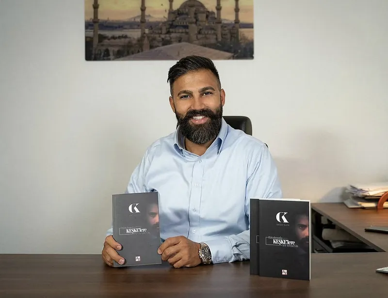 Ömer Kaya am Schreibtisch mit zwei Exemplaren seines Buches Hayatınızda Keşkelere Yer Vermeyin