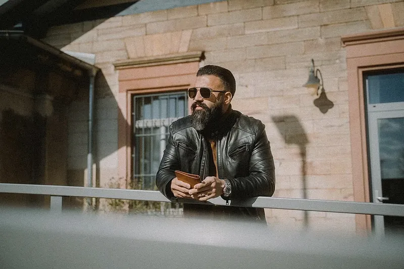 Ömer Kaya in Lederjacke mit Sonnenbrille an einem Geländer vor einem Sandsteinhaus in Wiesbaden