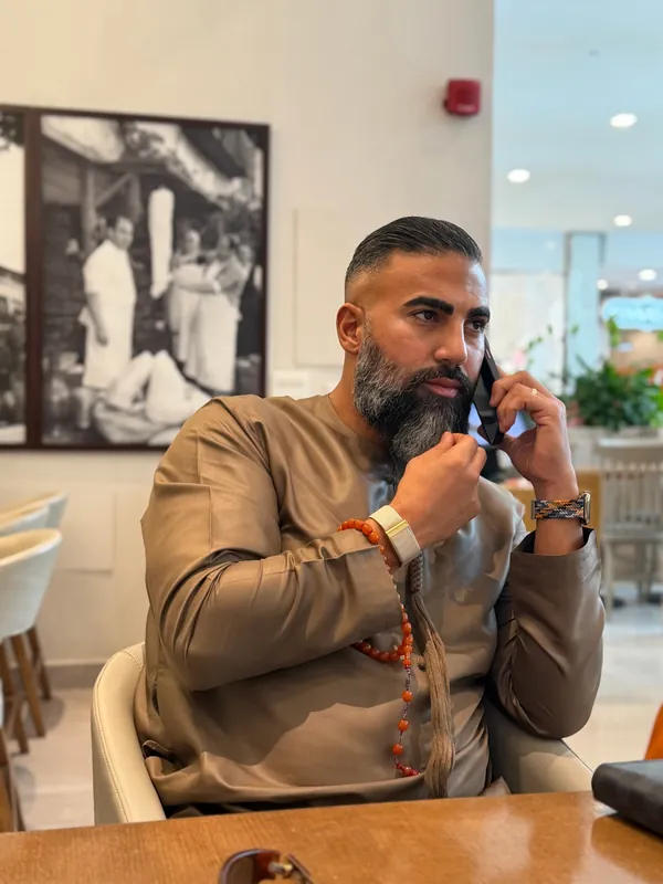 Ömer Kaya im braunen Kandura mit Gebetskette beim Telefonieren in einem Café in Dubai