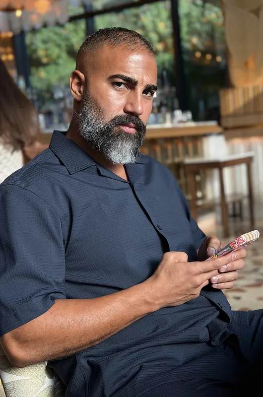 Ömer Kaya im dunkelblauen Hemd mit Telefon in einem Café in Dubai