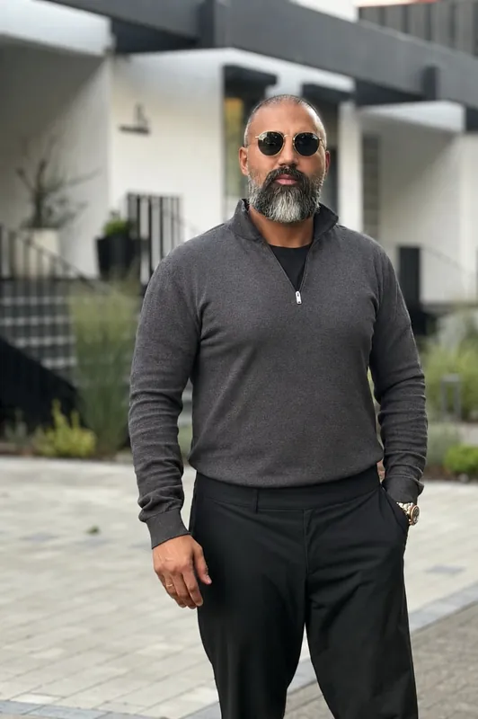 Ömer Kaya mit Sonnenbrille und grauem Pullover vor einer weißen Treppe in Wiesbaden