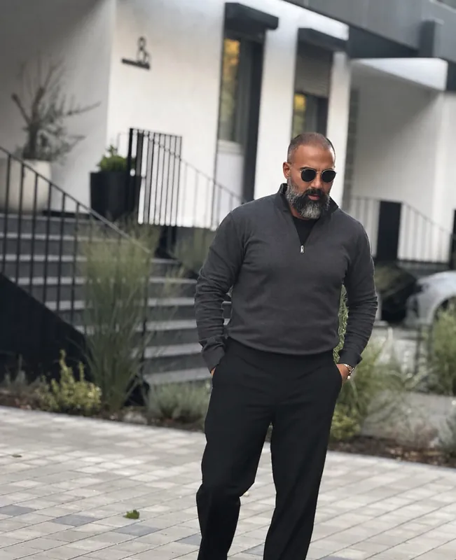 Ömer Kaya mit Sonnenbrille und grauem Pullover vor einer weißen Treppe in Wiesbaden