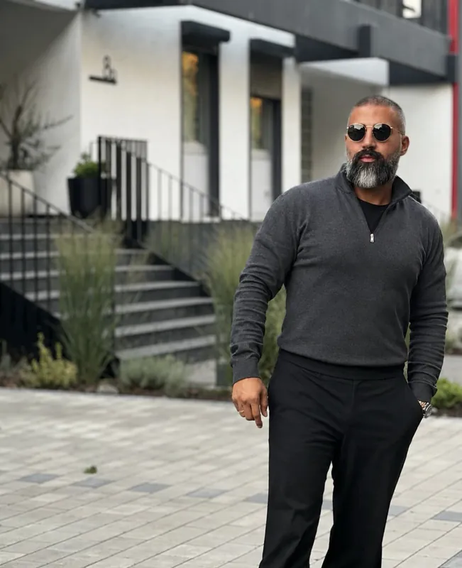 Ömer Kaya mit Sonnenbrille und grauem Pullover vor einer weißen Treppe in Wiesbaden